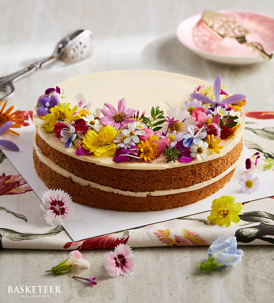 Vanilla butter cake with fresh edible flowers and white frosting, two-layer celebration cake