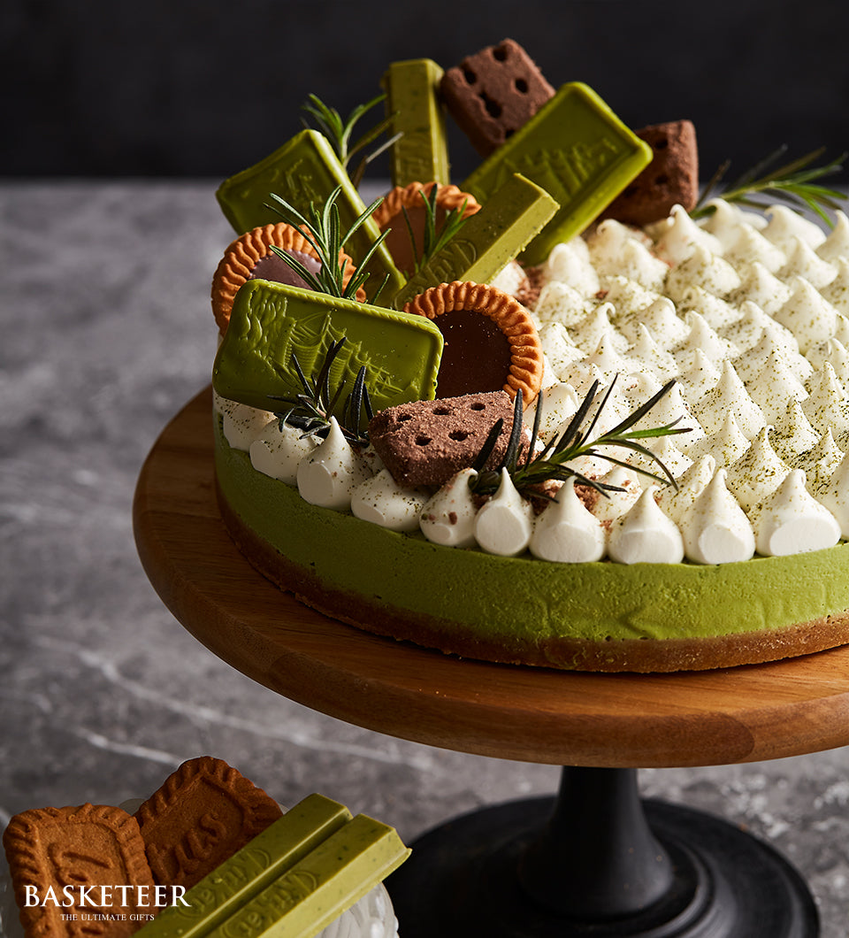 Matcha green tea cheesecake with whipped cream, chocolate decorations, and fresh rosemary on wooden stand