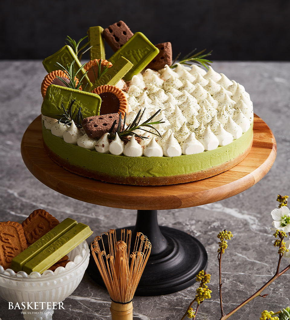 Matcha cheesecake with pistachio crust, whipped cream, and chocolate decorations on wooden stand