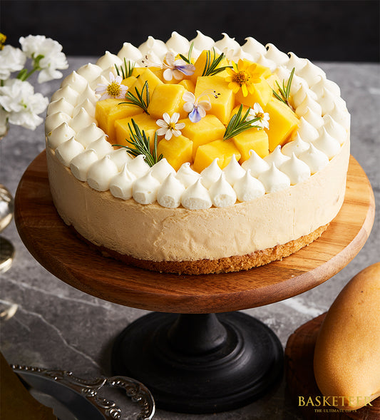 Vanilla mango mousse cake with white meringue, fresh mango, and edible flowers on wooden stand
