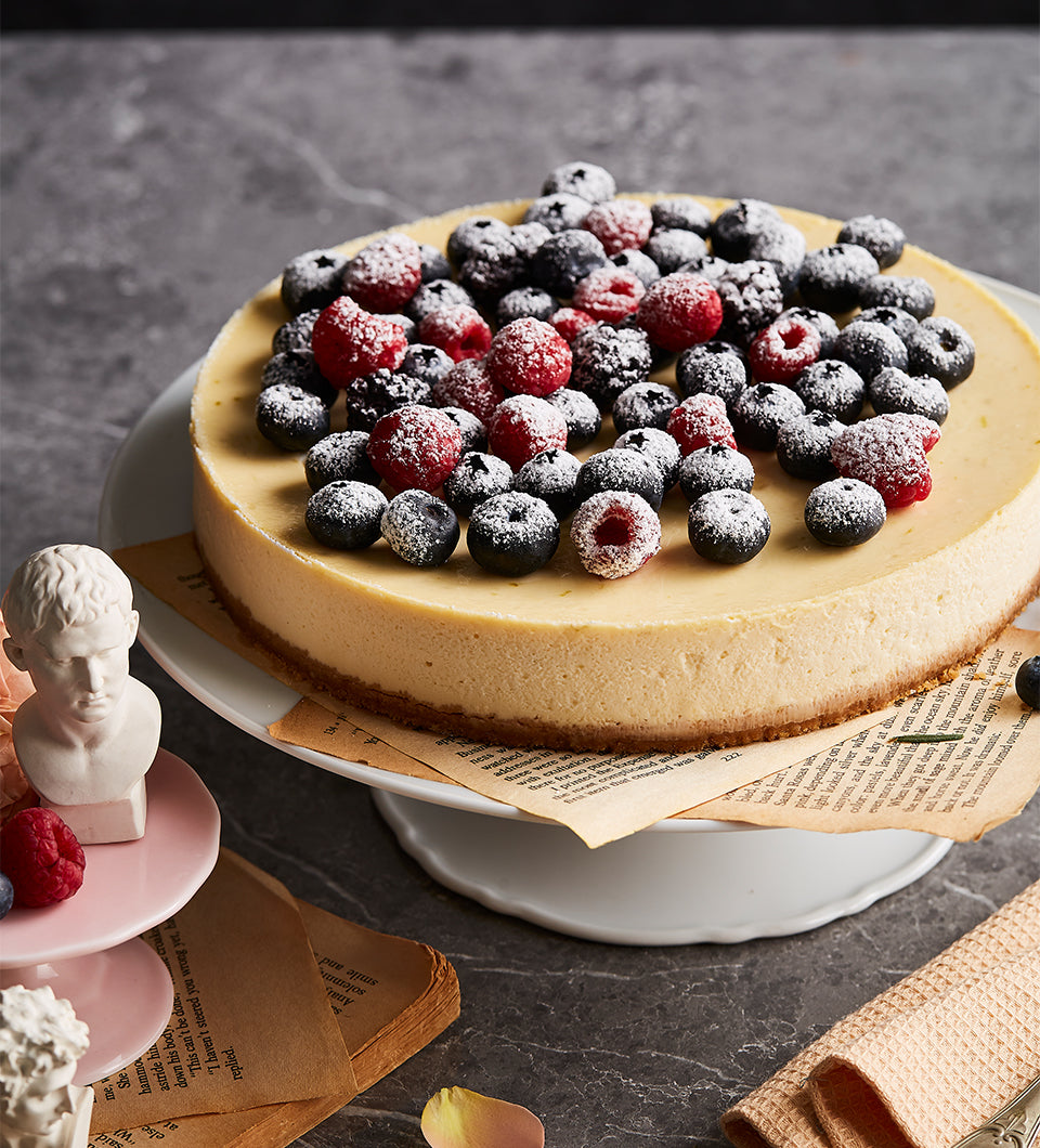 Mixed berry cheesecake with blueberries and raspberries on white ceramic stand, artisan birthday cake
