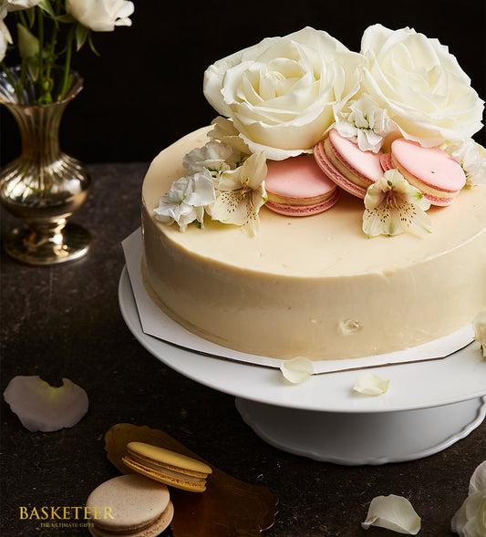 Vanilla mousse cream cake with white roses and pink macarons for birthday celebrations