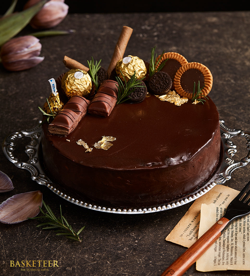 Decadent chocolate cake with Ferrero Rocher, Kinder Bueno, and gold leaf on silver serving tray