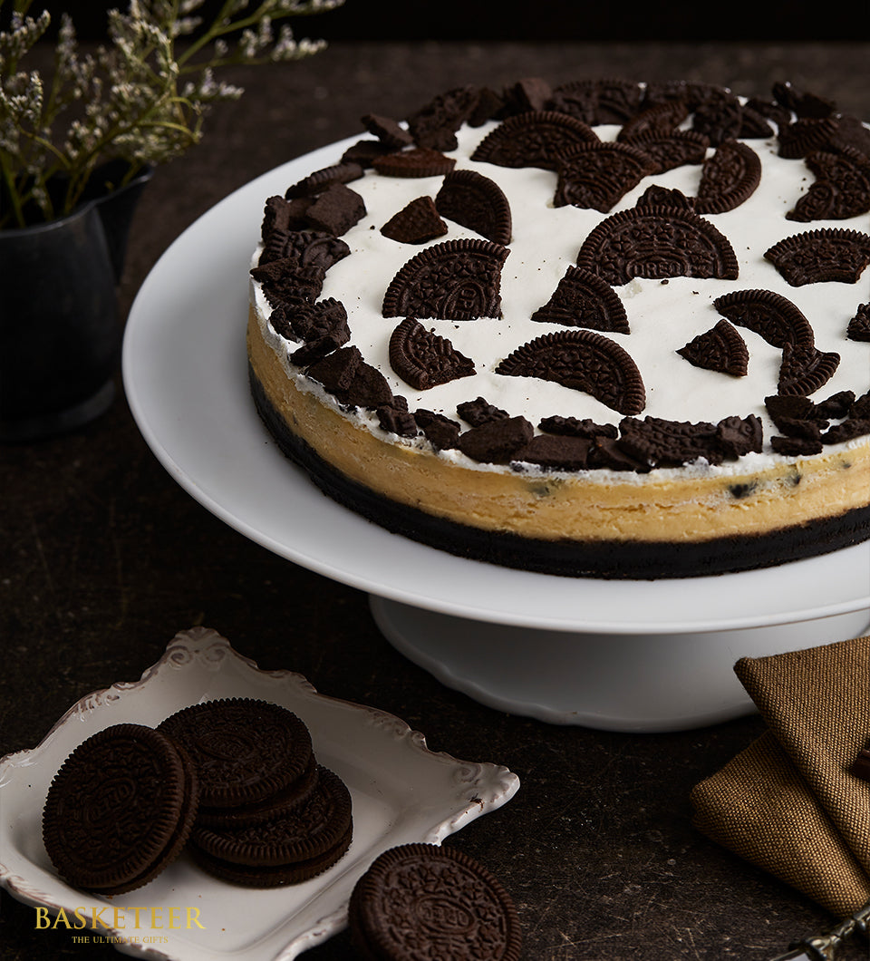 Oreo cheesecake with dark cookie crust, creamy filling, and white cream topping decorated with cookie pieces on ceramic stand
