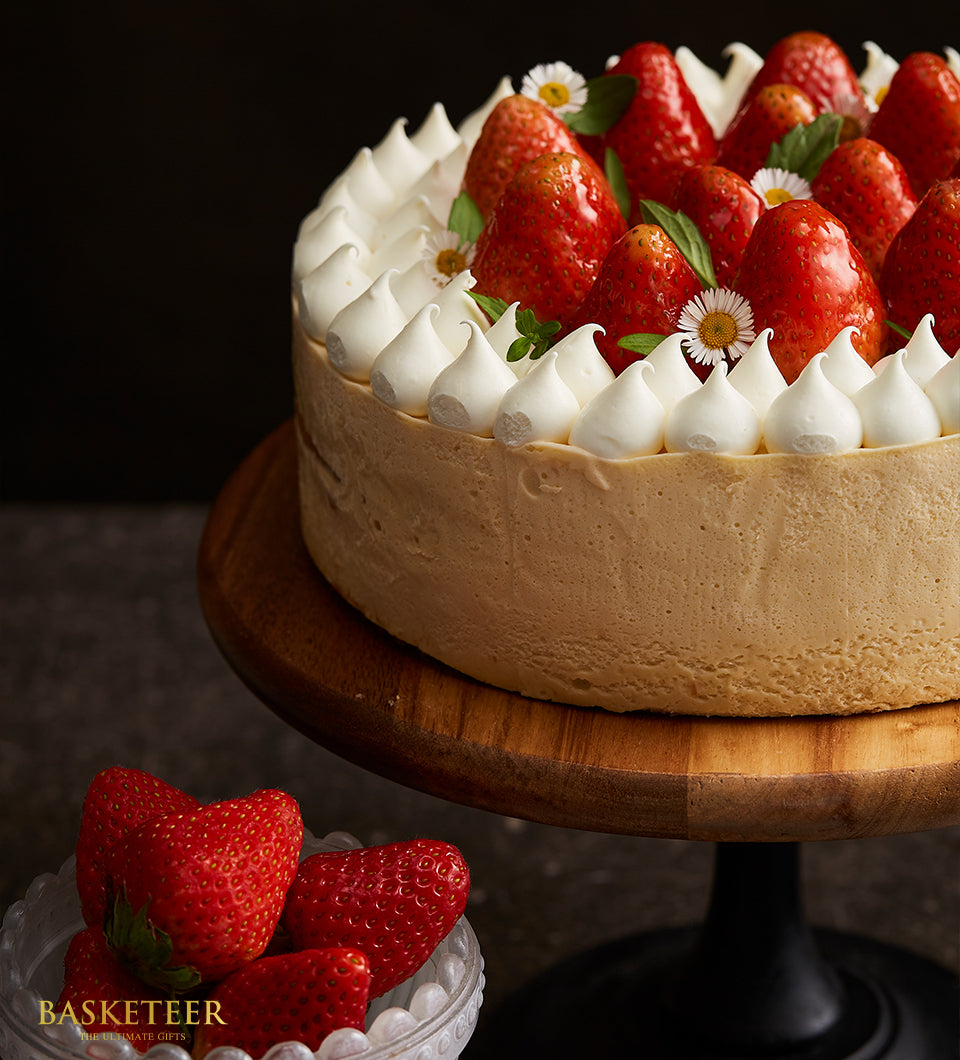 Strawberry swirl vanilla mousse cake with meringue peaks and fresh berries on wooden stand