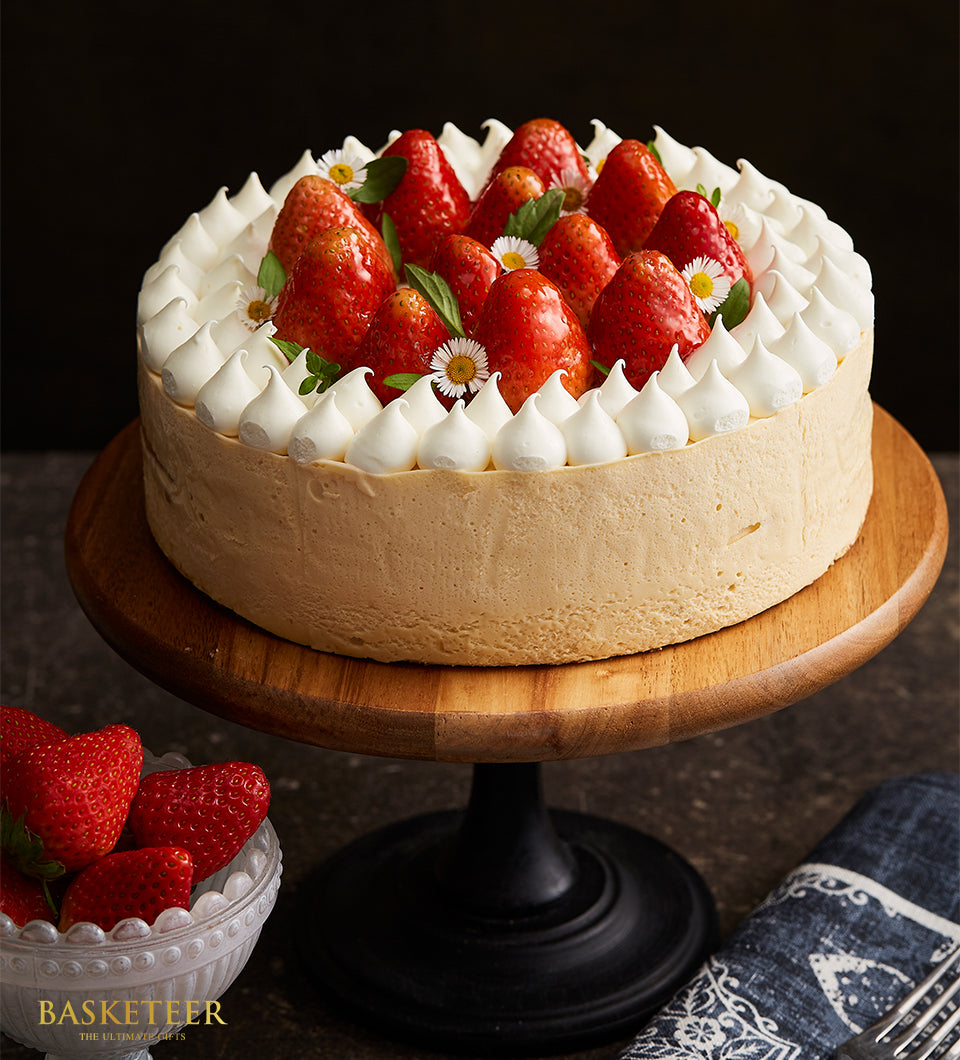 Strawberry Swirl Vanilla Mousse Cake with fresh berries and meringue peaks on wooden stand