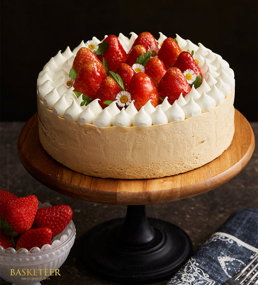 Strawberry Swirl Vanilla Mousse Cake with fresh berries and meringue peaks on wooden stand