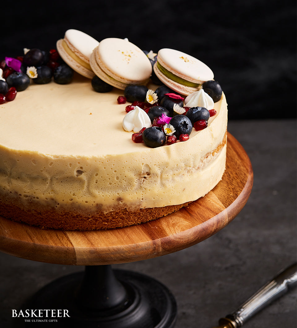 Creamy berry bliss cheesecake with blueberries, pomegranate, macarons and meringue on wooden stand