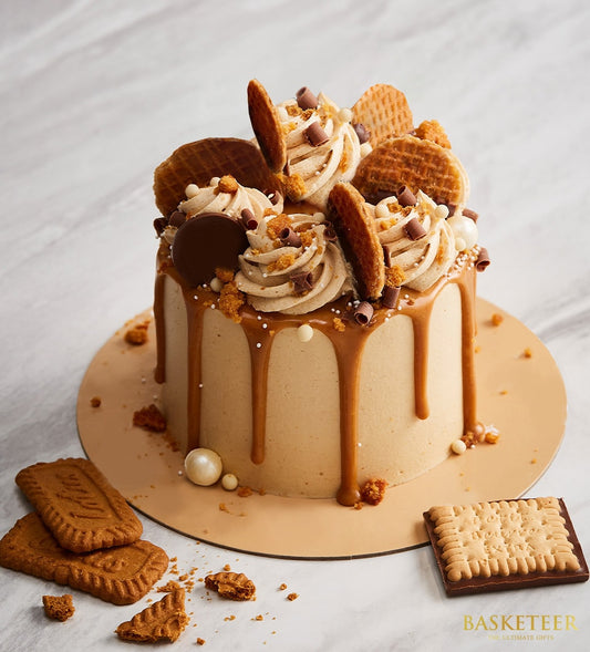 Biscoff caramel drip layer cake with chocolate curls and crushed biscuits, presented on cake board for birthday celebrations