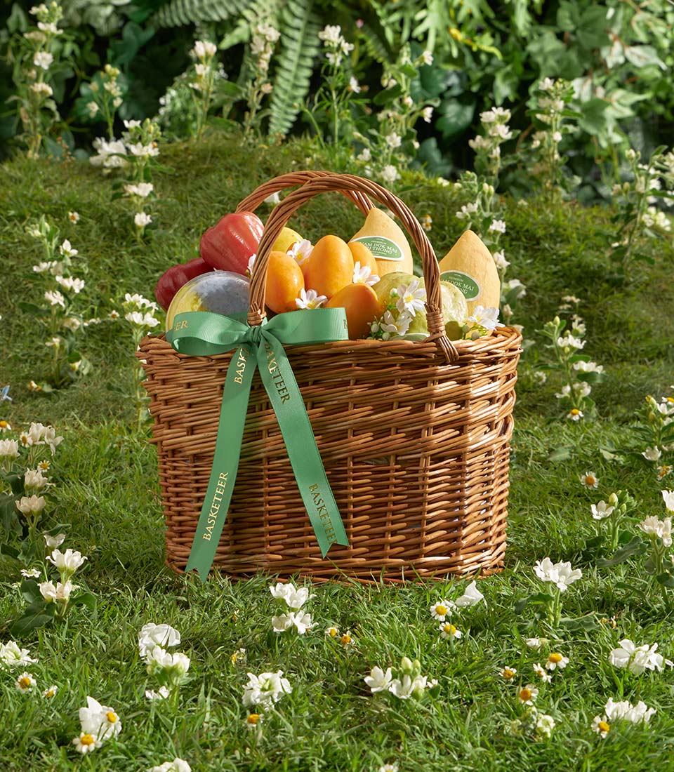 Golden Harvest wicker basket filled with fresh mangoes, rose apples, and guavas tied with green ribbon