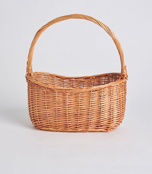 Handwoven light brown wicker basket with tall arched handle, ready for curated gift filling