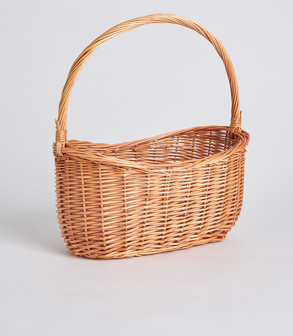 Light brown handwoven oval wicker basket with tall arched handle for premium gift packaging