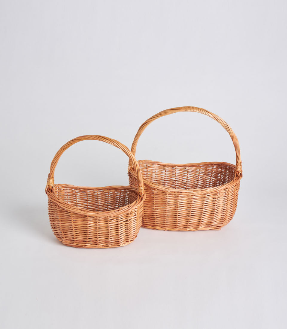 Light brown handwoven wicker baskets with tall handles, displayed in two sizes