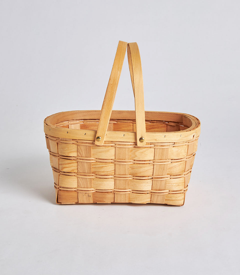 Handwoven light brown wicker basket with dual arched wooden handles, ideal for gourmet gift hampers