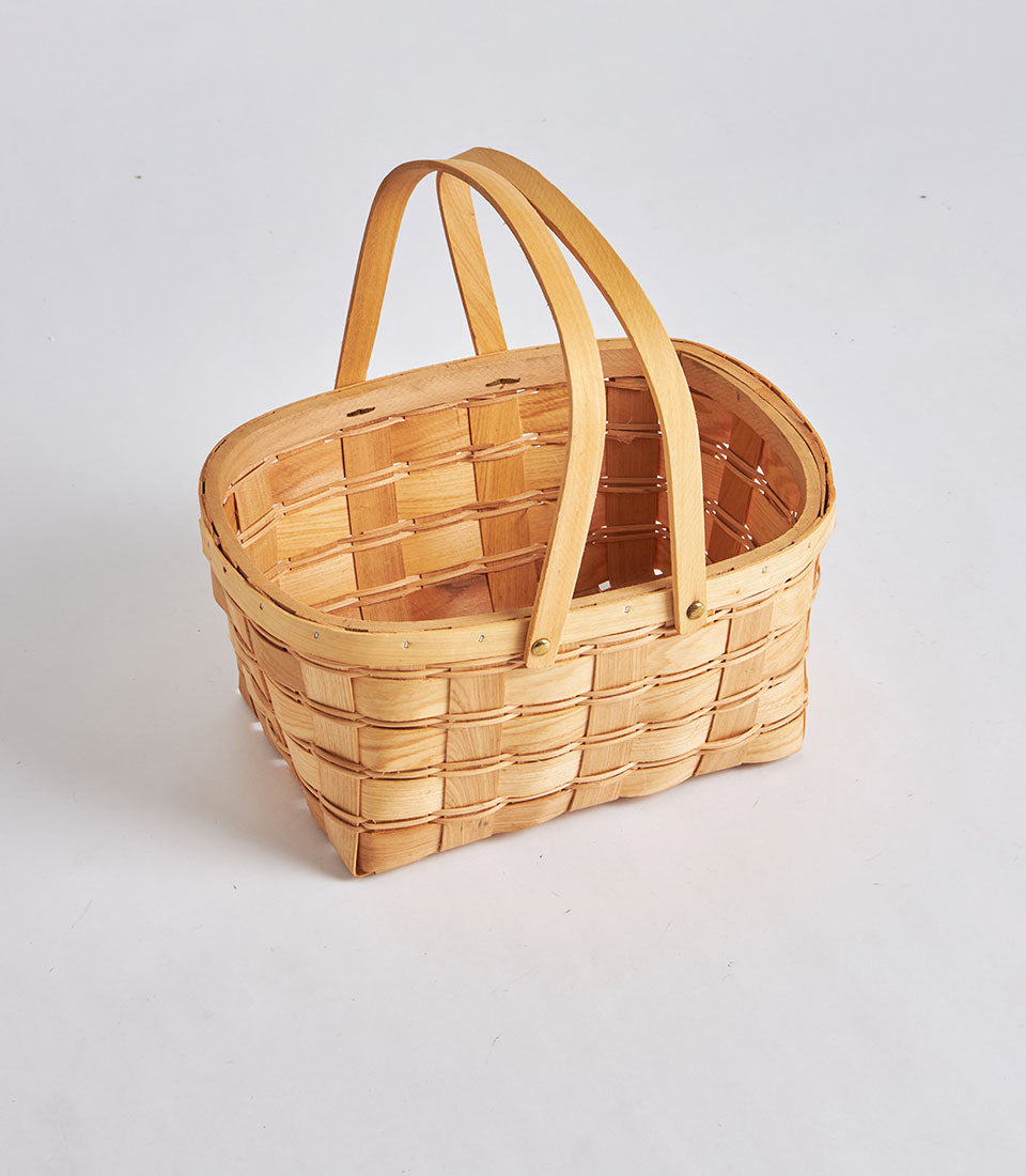 Light woven oval wicker basket with dual wooden handles, handcrafted for artisan gift hampers