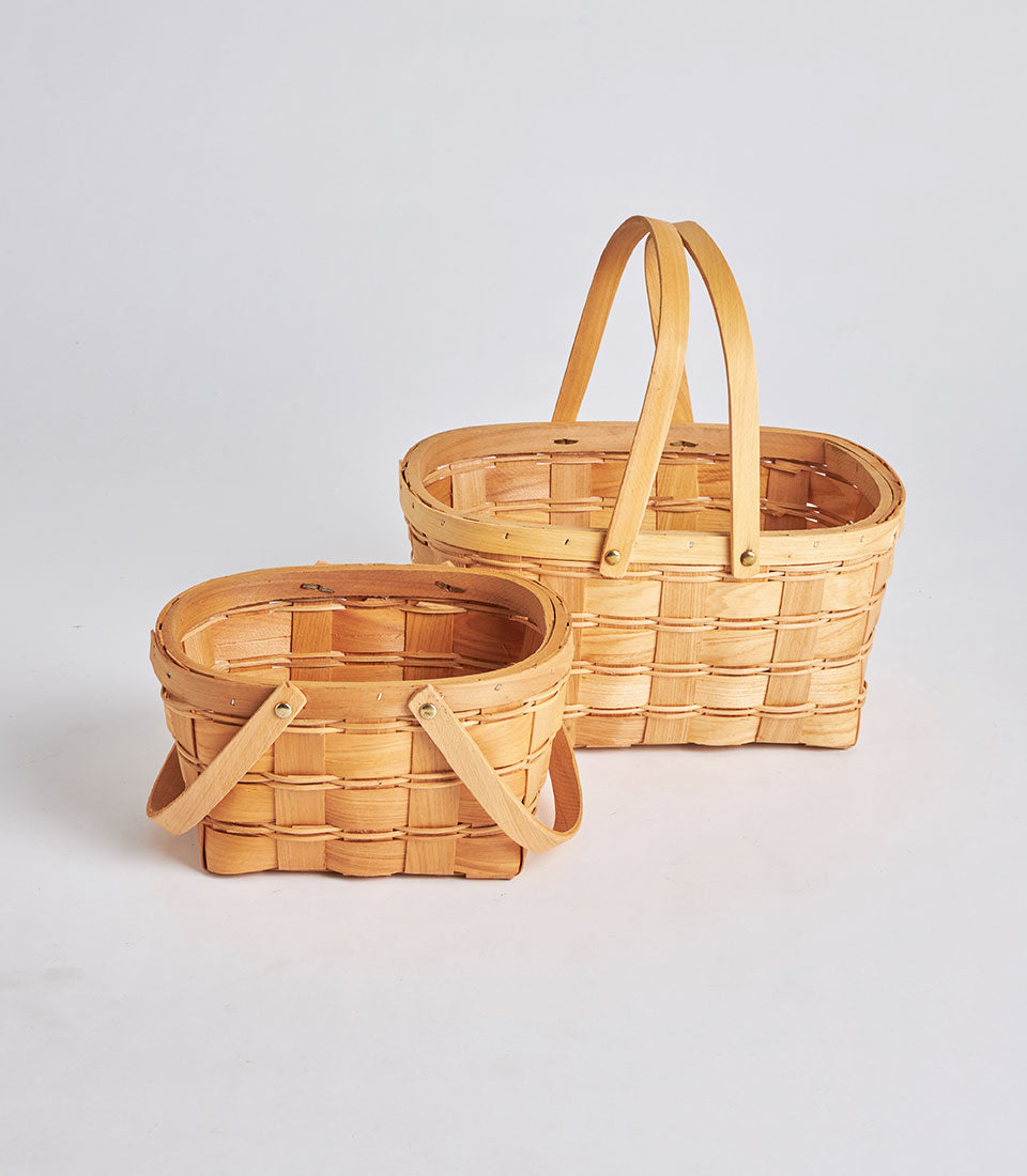 Light woven oval wicker baskets with brass handles, artisan gift hampers in natural wood finish