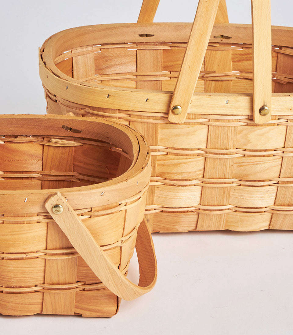 Handwoven oval wicker baskets with brass-handled double handles and natural wood finish