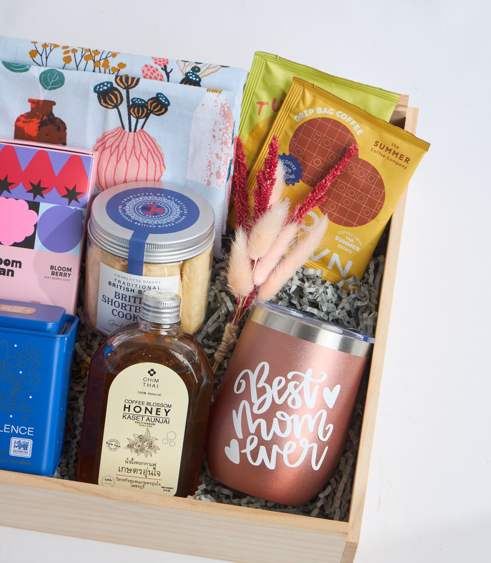 Curated gift box with wooden base containing coffee, honey, shortbread cookies, tea, drip bag coffee, dried flowers, and a rose gold "Best Mum Ever" tumbler.