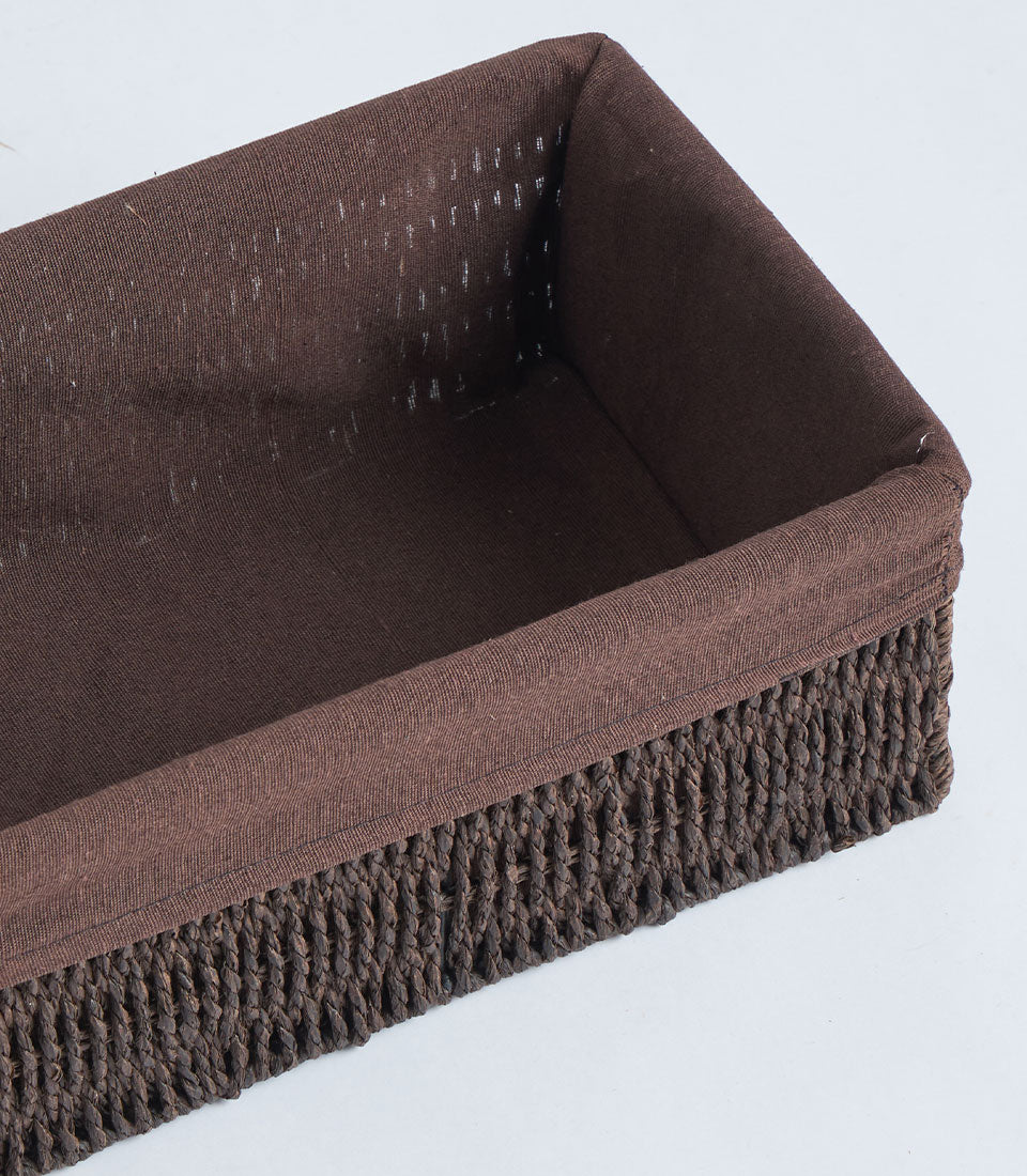 Handwoven rectangular wicker basket with brown fabric lining and rustic braided texture