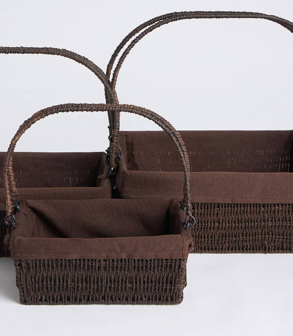 Set of three dark brown woven gift baskets with fabric liners and arched handles