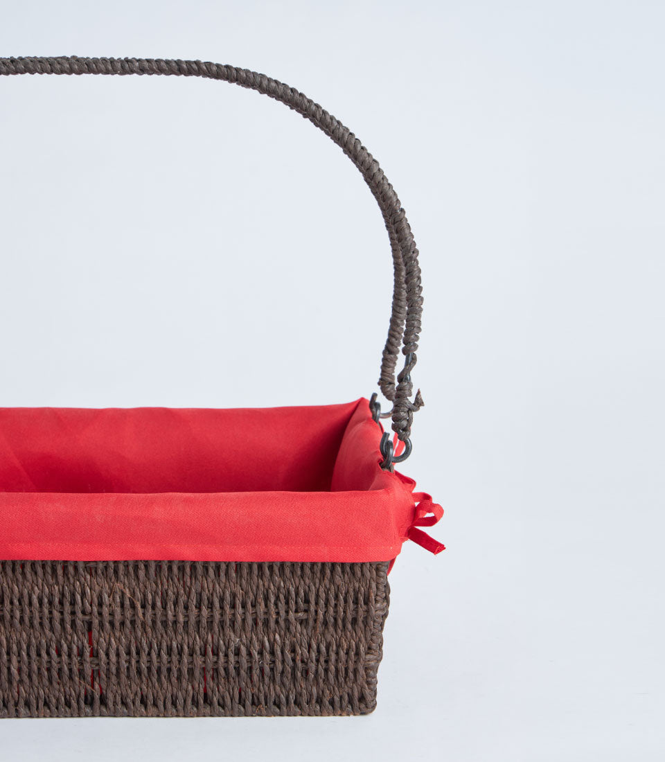 Handwoven rectangular wicker basket with red fabric liner and dark brown braided handle