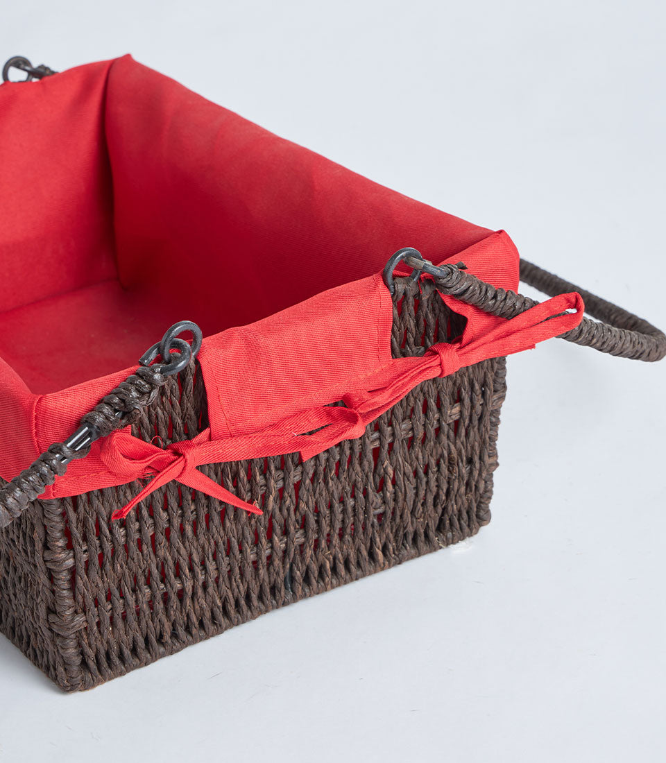 Handwoven dark brown wicker basket with red fabric liner and metal handle rings
