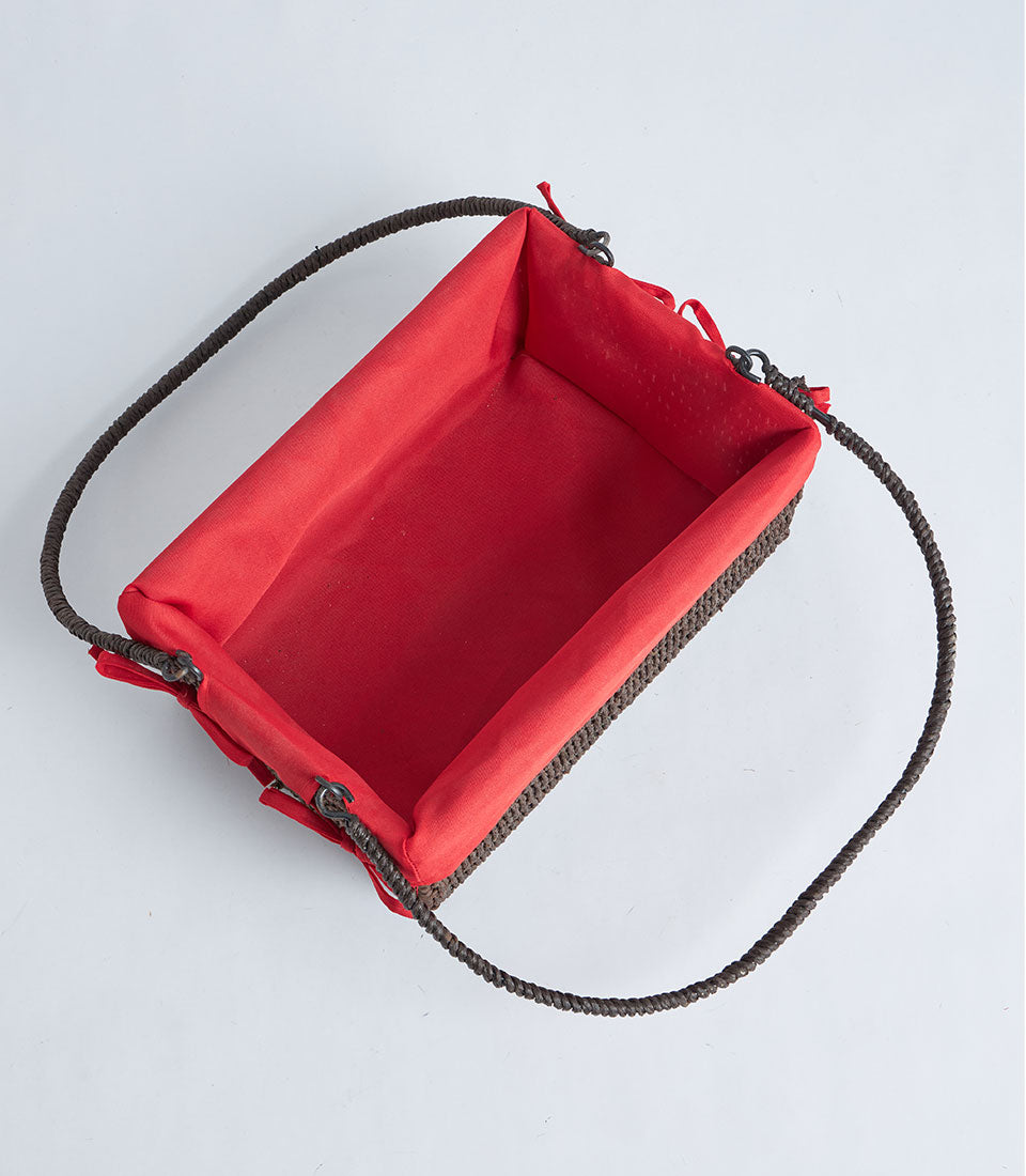 Handwoven rectangular wicker basket with red fabric lining and braided handle