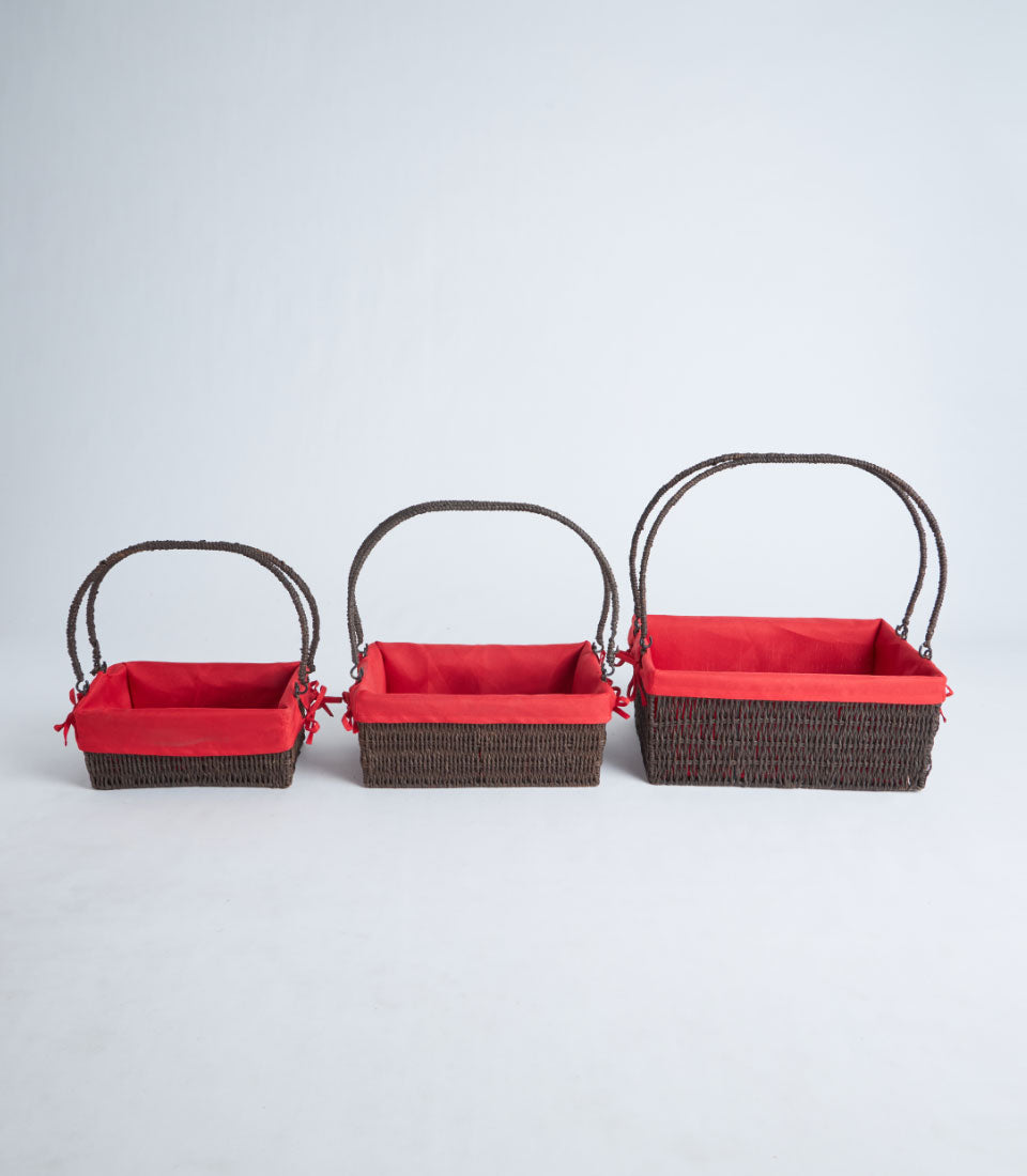 Handwoven wicker baskets with red fabric liners and ribbon handles in three sizes
