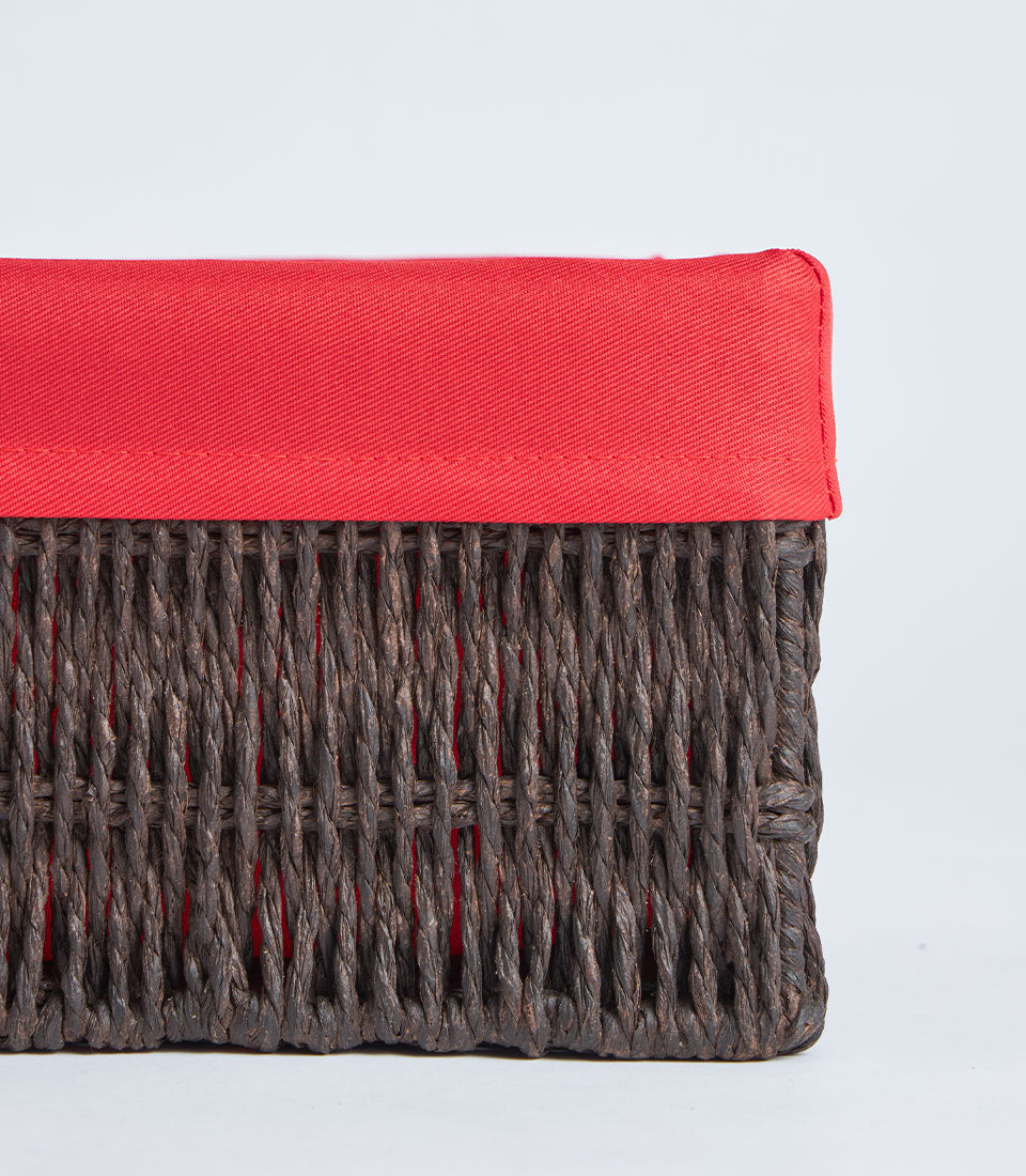 Handwoven wicker storage basket with vibrant red fabric lining and padded lid