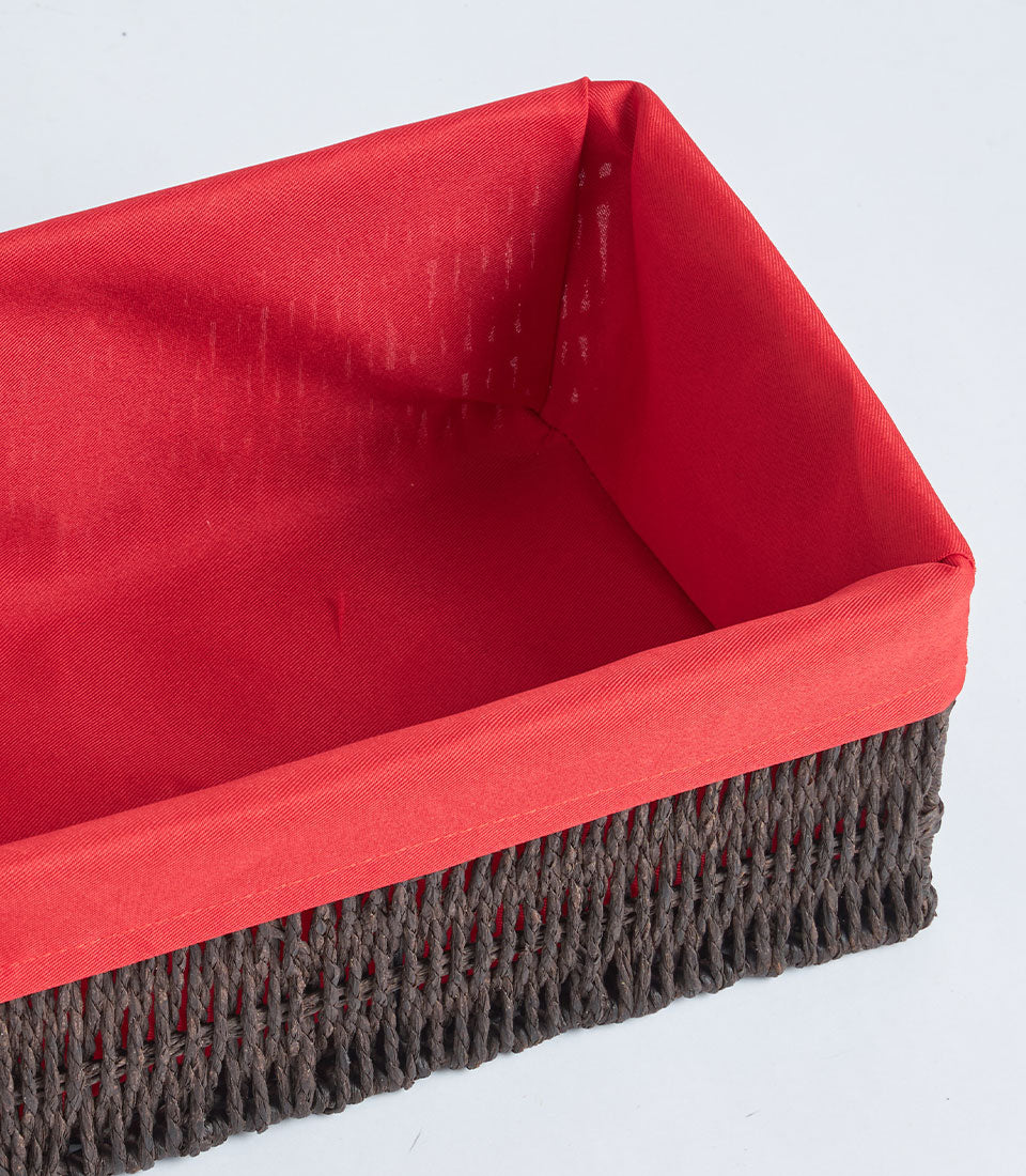 Handwoven rectangular wicker basket with bright red fabric lining and natural fiber weave