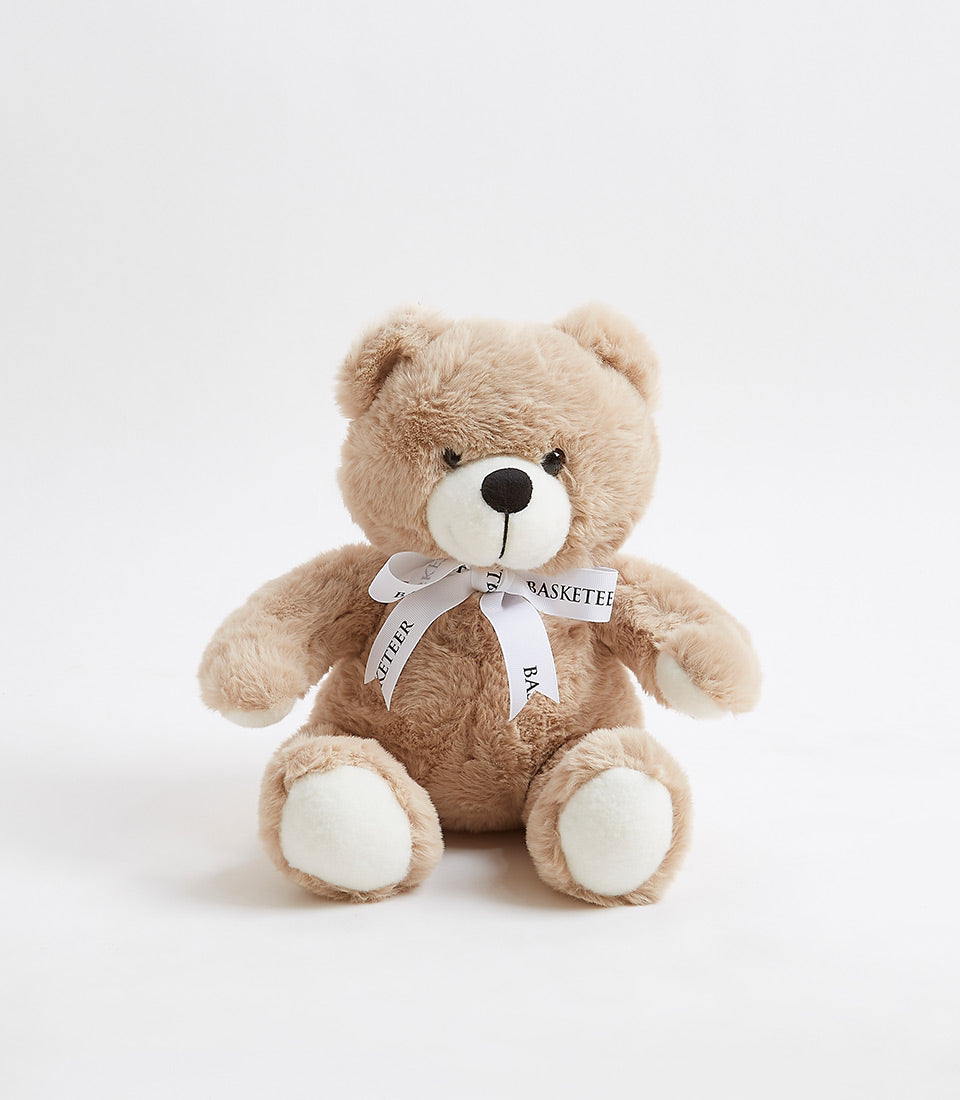 Tan fluffy teddy bear with white ribbon bow, perfect for baby gifts and children's celebrations