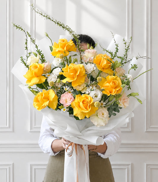 A vibrant Flowers by Basketeer rose bouquet featuring lush yellow roses, delicate white lis