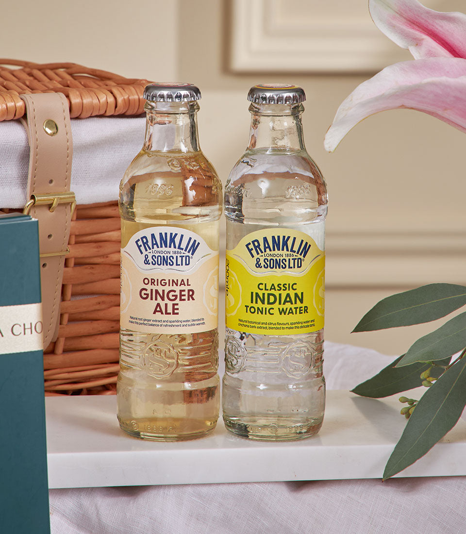 Premium ginger ale and tonic water bottles with woven basket for luxury New Year gift hamper