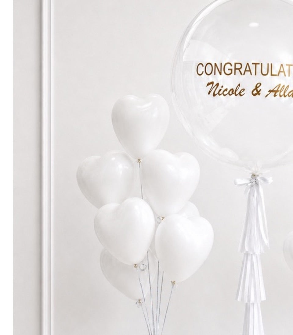 White heart-shaped balloons with congratulations message on clear bubble balloon, elegant wedding decoration with ribbons.