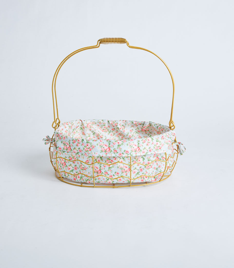 Gold oval wire basket with rose-patterned fabric lining and curved handle