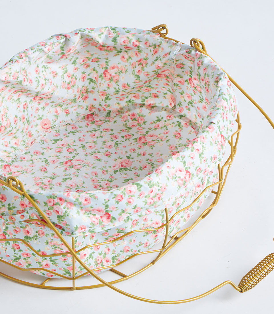 Gold oval wire basket with rose-patterned fabric liner and handle