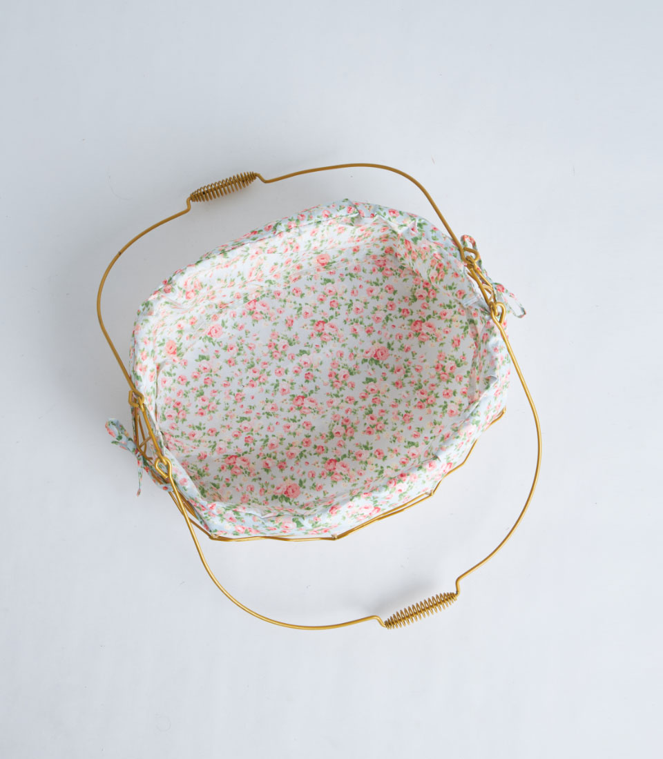 Gold metal oval basket with rose-patterned blue fabric lining and dual handles