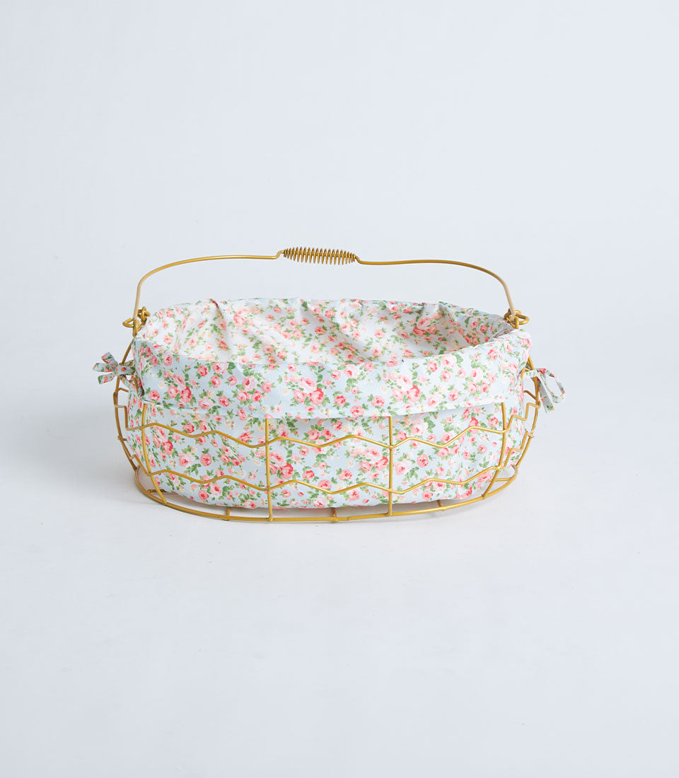 Gold oval wire basket with light blue floral fabric lining and handle
