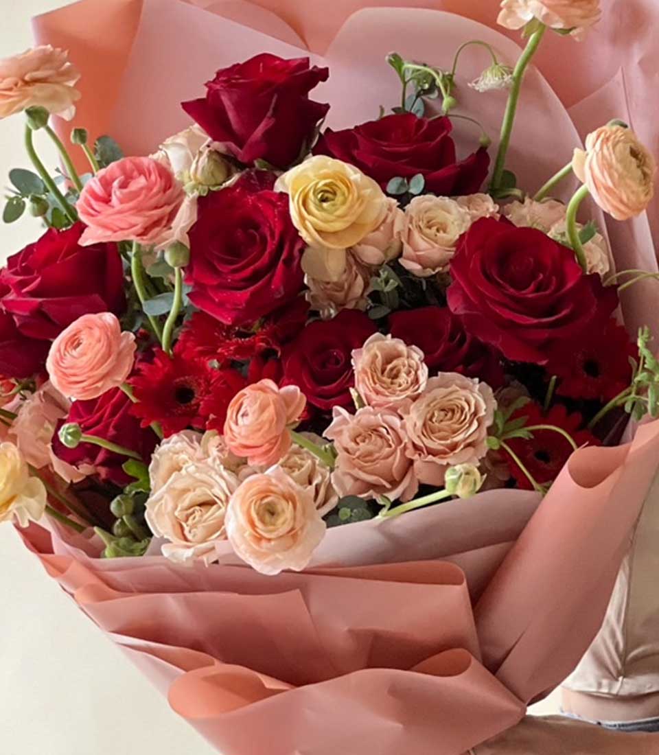 Passionate Crimson Rose Bouquet with peach ranunculus and soft pink wrapping for special occasions