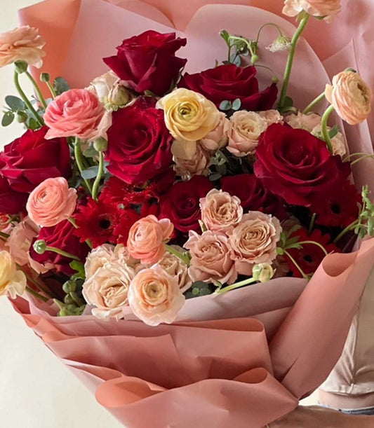 Passionate Crimson Rose Bouquet with peach ranunculus and soft pink wrapping for special occasions