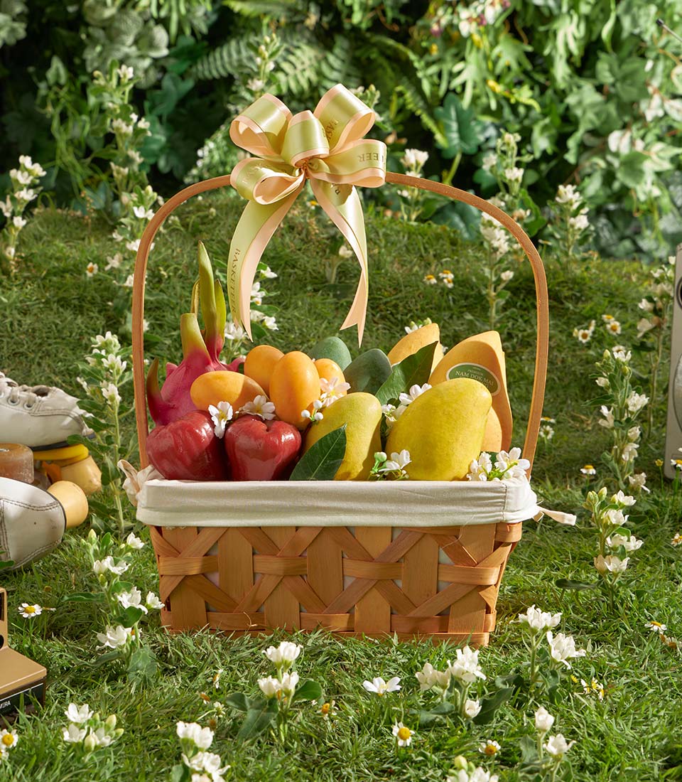 Premium tropical fruit basket with mangoes, papayas, and dragon fruit in woven wood with cream linen