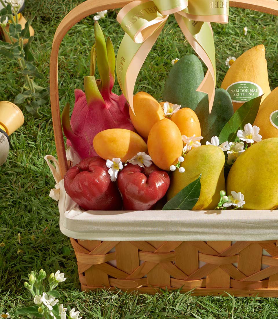 Luxury tropical fruit basket with premium Nam Doc Mai mangoes, dragon fruit, and rose apples in woven wooden hamper