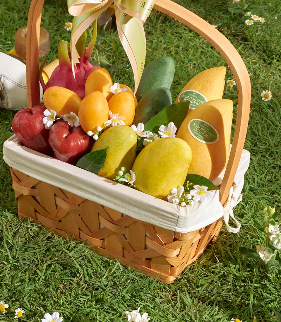 Premium tropical fruit basket with mangoes, rose apples, and pears in woven wood with white flowers