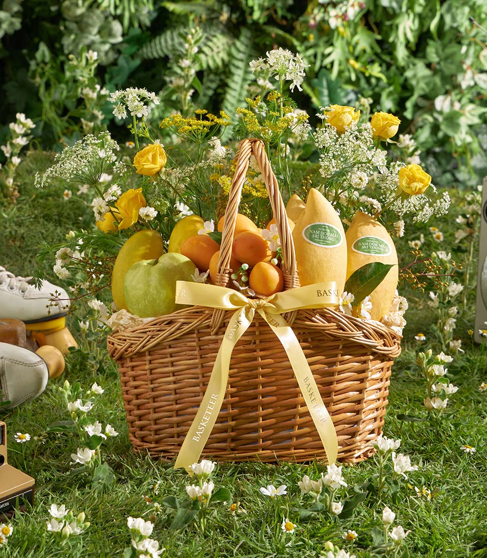 Premium mango and tropical fruit basket with yellow roses and white flowers in wicker hamper