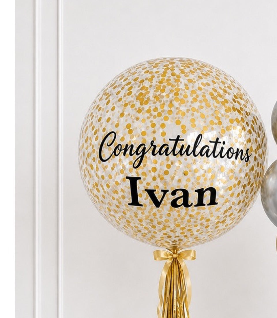 Gold confetti-filled clear balloon with "Congratulations Ivan" text and gold tassel, elegant celebration decor.