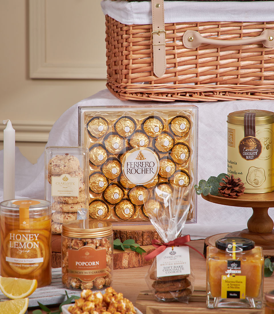 Golden gourmet breakfast hamper with Ferrero Rocher chocolates, honey syrup, Charlotte cookies, and caramel popcorn in