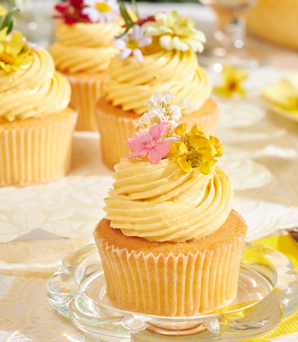 Golden mango buttercream cupcakes with fresh flowers, artisan celebration desserts
