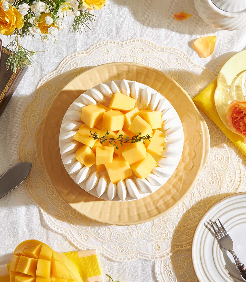 Golden mango chiffon layer cake with fresh mango cubes and whipped cream on ceramic plate