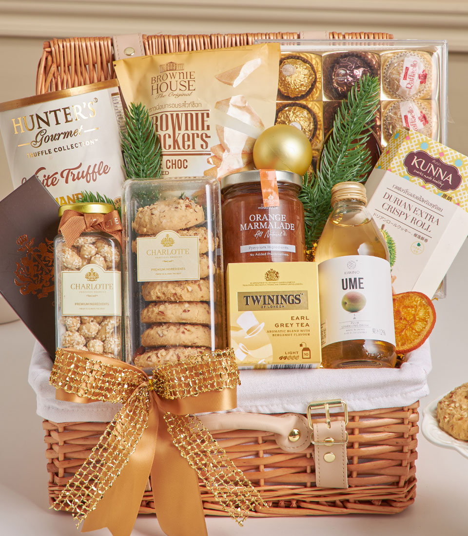 Wicker gift hamper with truffle chips, gourmet cookies, chocolate, tea, and marmalade tied with gold ribbon for New Year