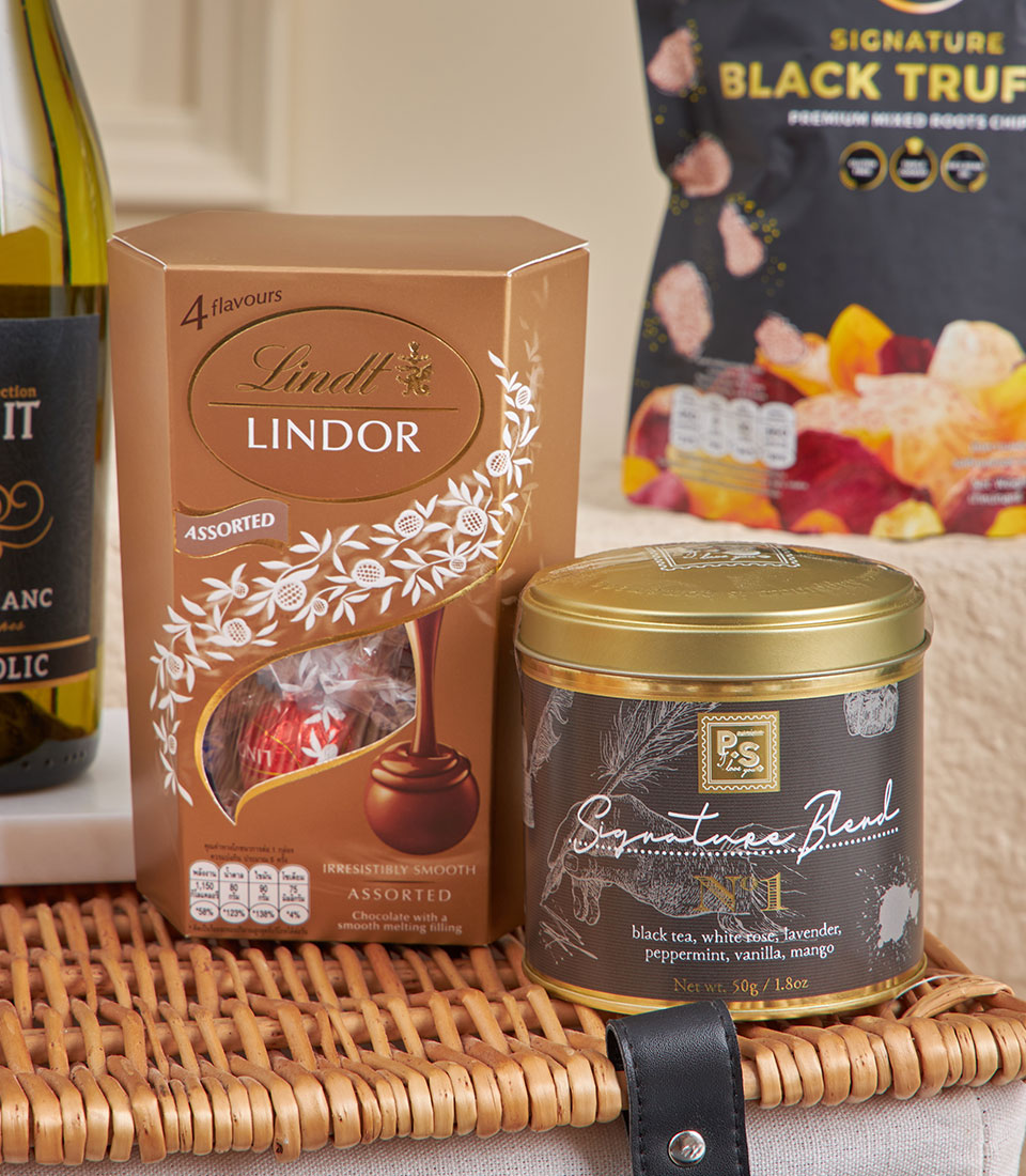 Luxury chocolate and tea gift hamper with Lindt truffles, artisan blend tea, and gourmet snacks in woven basket